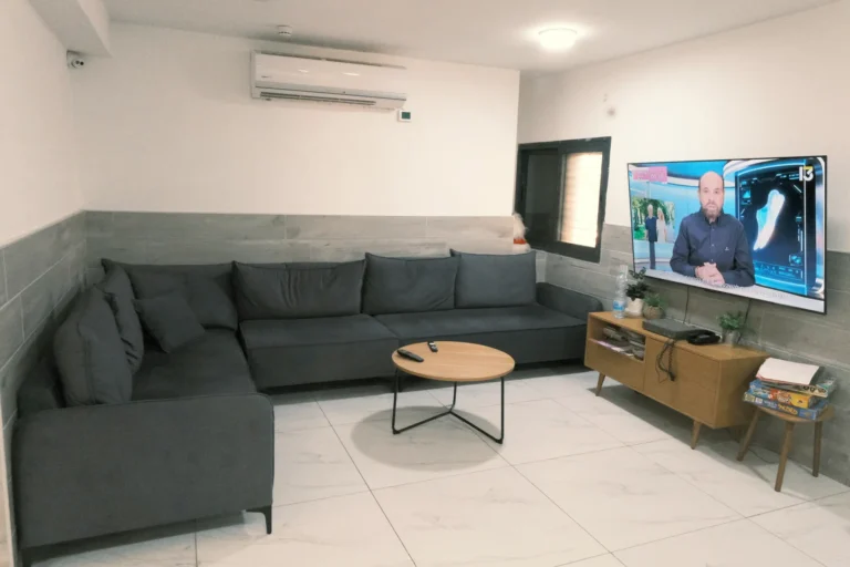 סלון עם ספה גדולה וטלוויזיה במעון אביב